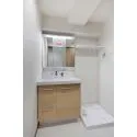 マンション弦巻 水栓周りに水がたまらず衛生的な、ハイバック仕様の洗面化粧台。洗濯機置き場上部に棚が設けられています。